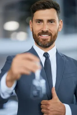 Man showing thumb up and holding keys from new car