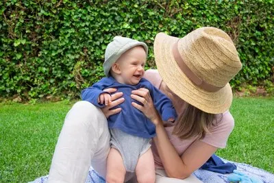Young mom with face covered by hat holding daughter