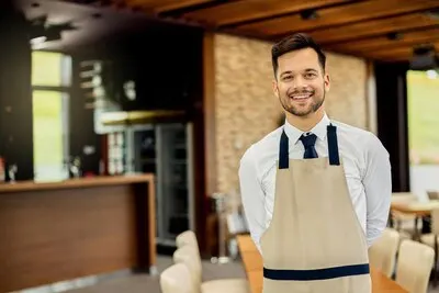 Portrait of a young happy waiter in a cafe