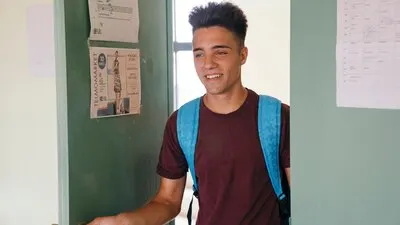 Young boy with backpack coming into the classroom
