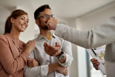 Closeup of a real estate agent giving to a couple keys of their new home