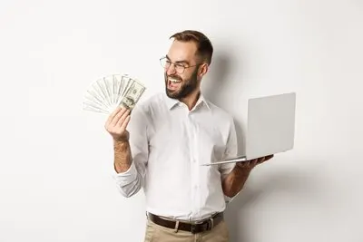 Business and e-commerce. Successful businessman using laptop for work and holding money, standing