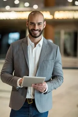 Portrait of smiling businessman using digital tablet in waiting area