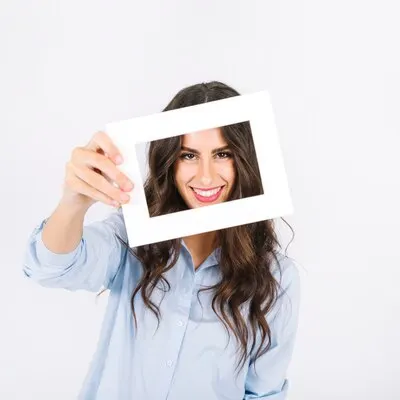 Joyful woman holding frame in front of face