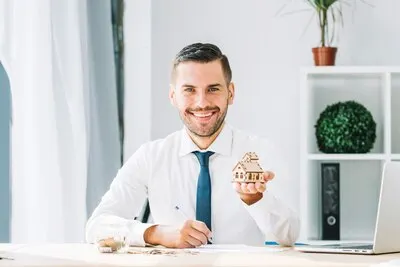 Cheerful real estate agent showing toy house
