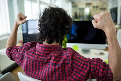 Male graphic designer cheering in office
