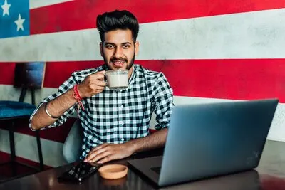 Handsome, young  american business man, freelancer  in casual clothes in bar, relaxing with cup of coffe.