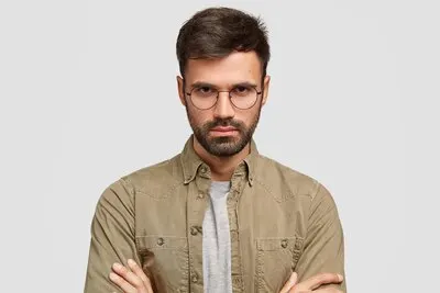 Photo of serious handsome guy posing against the white wall