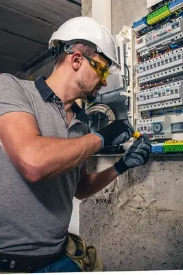 Man an electrical technician working in a switchboard with fuses