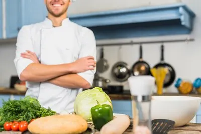 Chef in kitchen in front of vegetables
