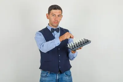 Young man in suit, jeans holding chessboard and figure