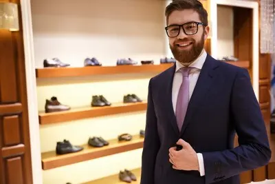 Happy man in suit and glasses stading near shelf