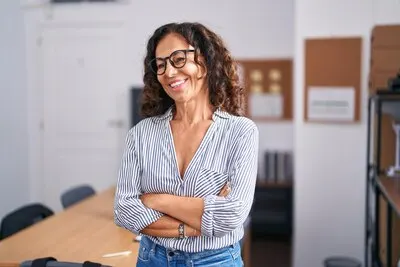 Middle age woman business worker smiling confident standing with arms crossed gesture at office