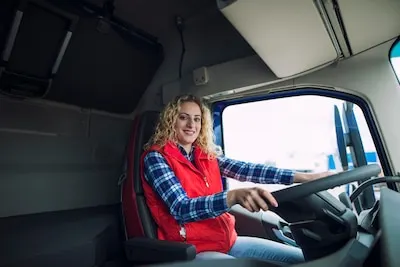 Camionera con chaleco rojo sentada al volante en la cabina de un camión